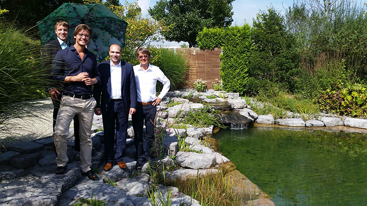 Garten- und Landschaftsgärtner arbeiten nicht nur mit Pflanzen, sondern schaffen auch Schwimmträume: Rudolf (rechts) und Johannes Haderstorfer (Zweiter von links) zeigen MdB Florian Oßner (Zweiter von rechts) mit Julian Herold (links) vom Verband Garten-, Landschafts- und Sportplatzbau Bayern das Felsenbad auf dem Firmengelände in Ergolding. 